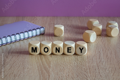 Money symbol. Writing the word Money on wooden cubes. Beautiful wooden table, purple background. Notebook. Business concept. photo