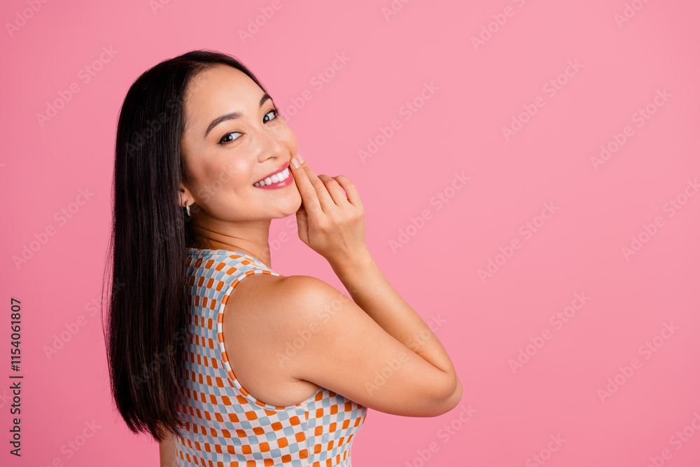 Young asian woman smiling playfully against a vibrant pink background wearing a stylish summer outfit, showcasing her charming personality