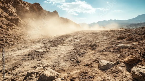Dusty rocky landscape with rugged terrain under a bright sky capturing sunlight in a dry natural environment.