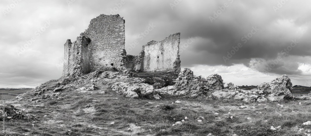 Ruins of an ancient castle set against a dramatic sky showcasing the passage of time and history in a black and white landscape. Ruins of an ancient castle set against a dramatic sky showcasing the passage of time and history in a black and white landscape.