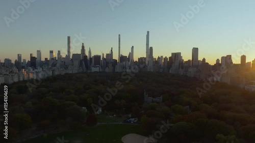 Aerial views showcase a sunset over Central Park, illuminating vibrant trees against the iconic Midtown Manhattan skyline. Warm evening light enhances the scene