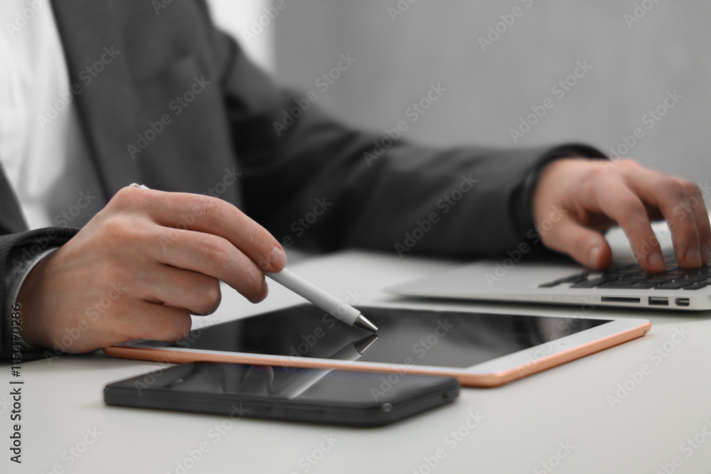 Businessman using different devices at white table indoors, closeup. Modern technology Businessman using different devices at white table indoors, closeup. Modern technology