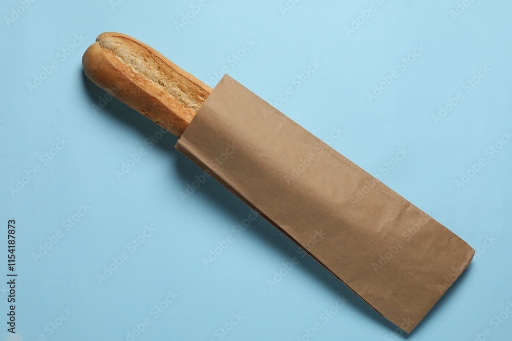 Paper bag with fresh baguette on light blue background, top view Paper bag with fresh baguette on light blue background, top view