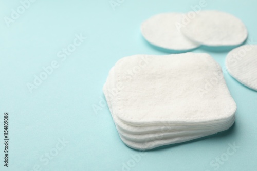 Clean cotton pads on light blue background, closeup. Space for text