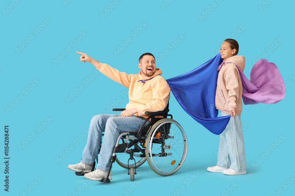 Little girl and her father in wheelchair with superhero capes on blue background Little girl and her father in wheelchair with superhero capes on blue background