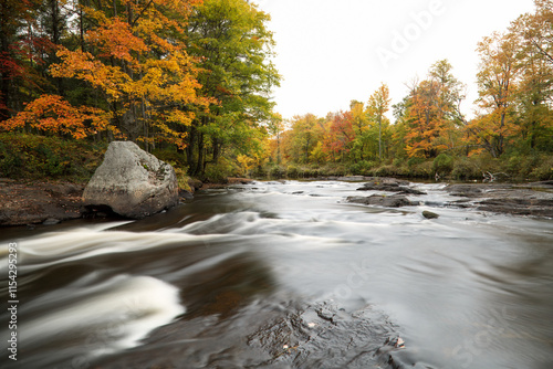 Long exposure river rapids from rocks in the middle of the river, surrounded by autumn fall colors.