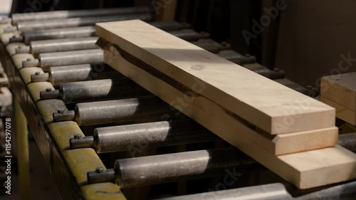 Logs are lying on the machine and are being prepared for cleaning. Beautiful sunbeams fall on the sawn boards. Beautiful wooden surface. Smooth logs, boards.