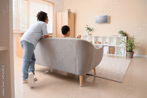 Cute African-American children watching cartoons on TV at home, back view