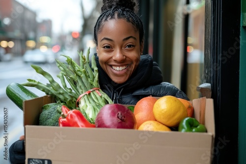 Smiling woman holding a large box filled with fresh vegetables and fruits in an urban setting, showcasing healthy lifestyle and community engagement