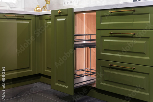 Open drawer in a green kitchen cabinet photo