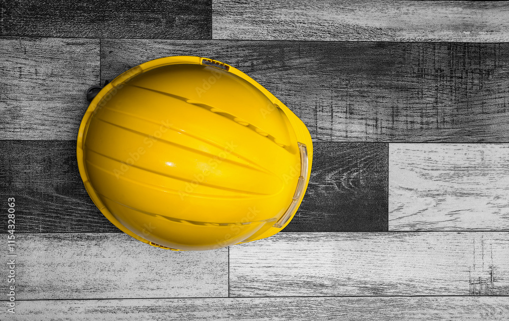 Yellow hard hat resting on wooden floor boards emphasizing workplace safety