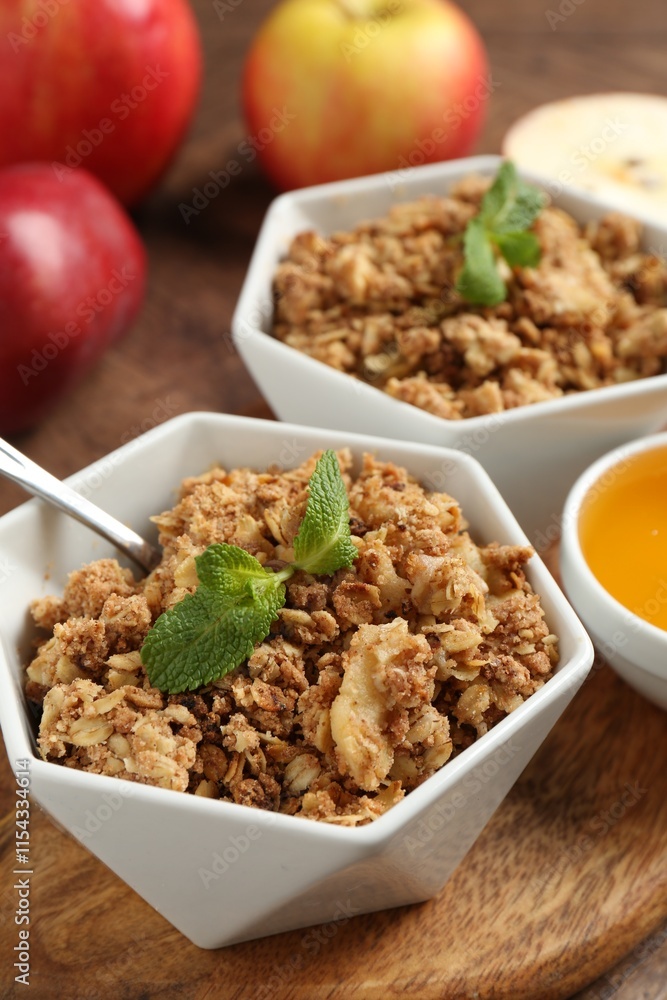 Tasty apple crisp in bowls, fresh fruits, honey and spoon on table, closeup Tasty apple crisp in bowls, fresh fruits, honey and spoon on table, closeup