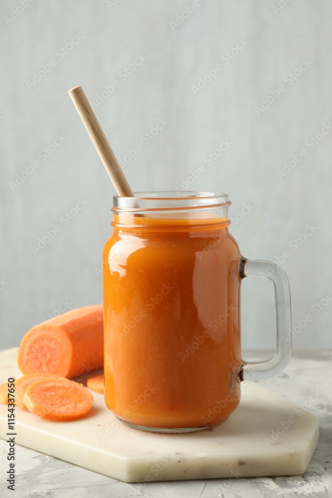 Fresh carrot juice in mason jar and vegetable on gray textured table Fresh carrot juice in mason jar and vegetable on gray textured table