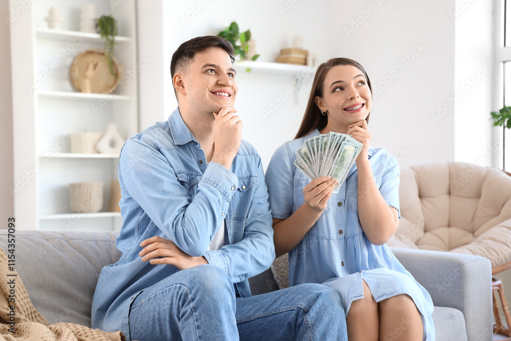 Dreaming young couple with money sitting on sofa at home Dreaming young couple with money sitting on sofa at home