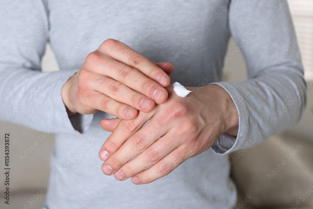 Man applying cream on his hands indoors, closeup Man applying cream on his hands indoors, closeup