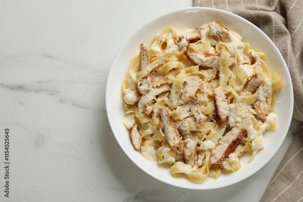Tasty Alfredo pasta with chicken on white marble table, top view. Space for text Tasty Alfredo pasta with chicken on white marble table, top view. Space for text