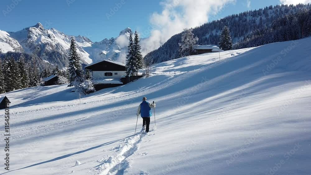 A man is hiking into a deep snow path heading towards the mountain peak under a beautiful sunny sky. A man is hiking into a deep snow path heading towards the mountain peak under a beautiful sunny sky.