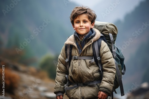 Portrait of a cute little boy with backpack on the background of mountains photo