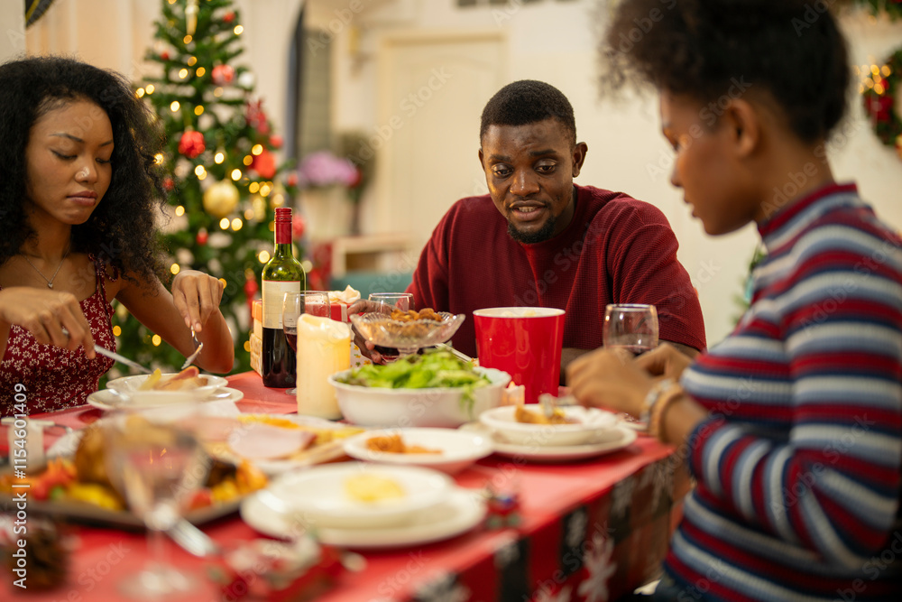 A joyful family shares a Christmas meal together, passing food and creating holiday memories. Decorated tree, festive lights, and presents in the background add warmth to cozy celebration atmosphere. A joyful family shares a Christmas meal together, passing food and creating holiday memories. Decorated tree, festive lights, and presents in the background add warmth to cozy celebration atmosphere.