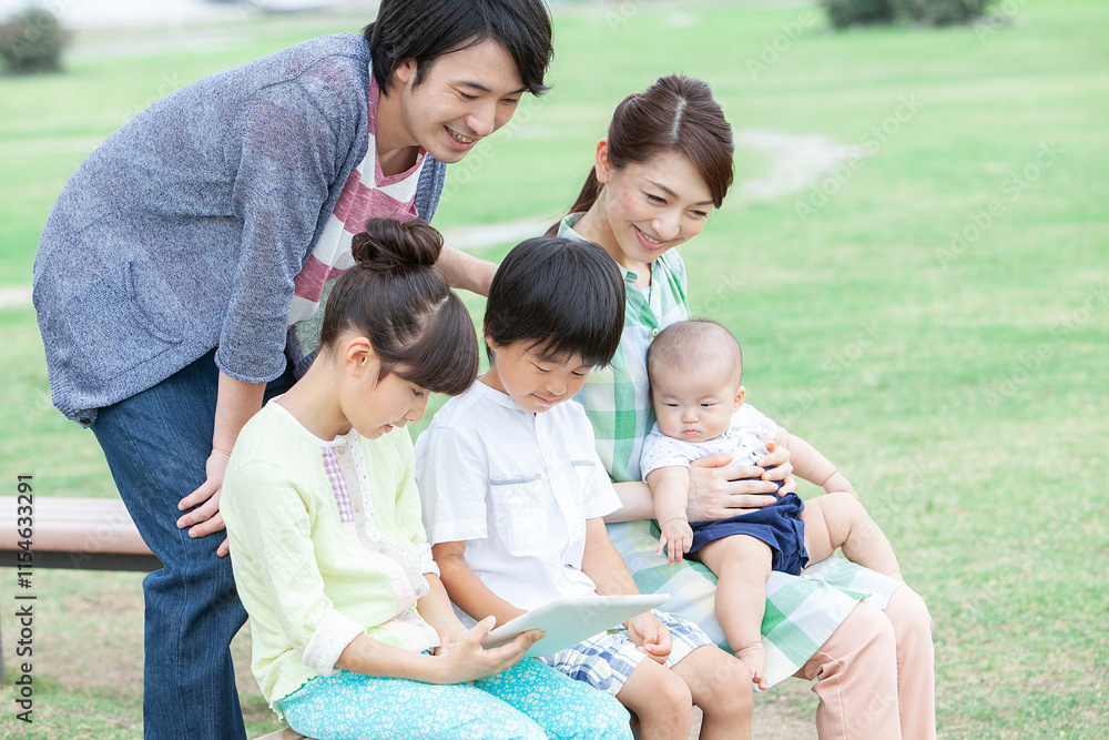 公園でタブレットを操作する家族 公園でタブレットを操作する家族