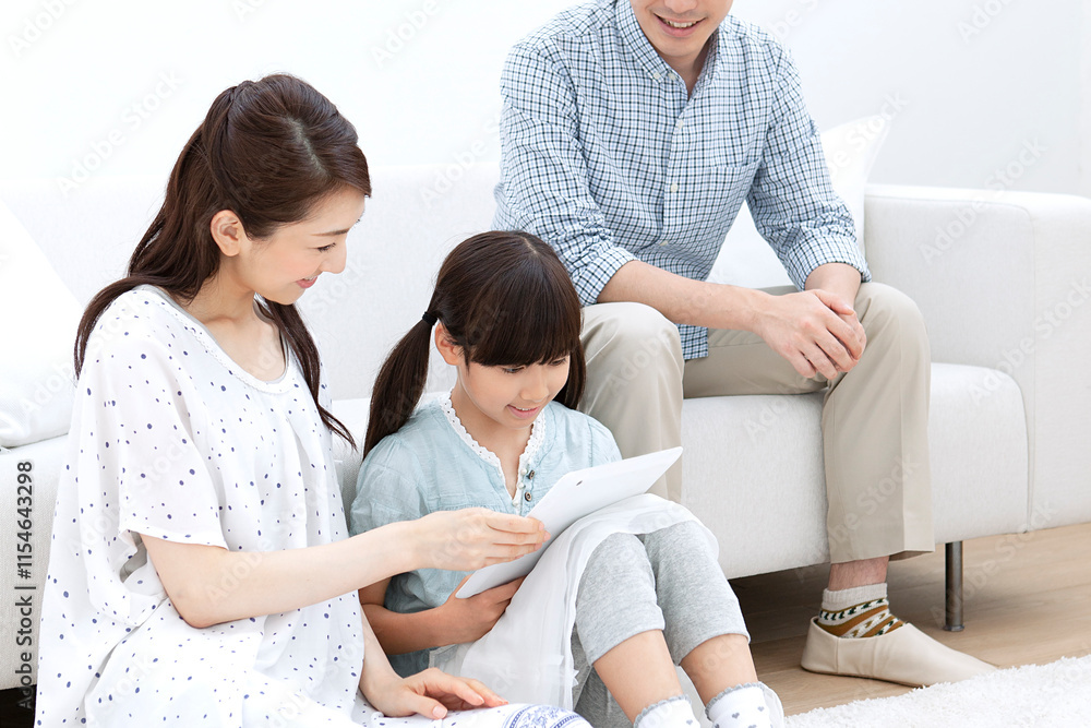 Obraz premium リビングでタブレットを操作する家族