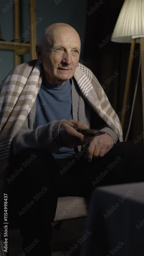 Elderly man holding remote control changing tv channels expressing shocked expression getting nervous from bad news Elderly man holding remote control changing tv channels expressing shocked expression getting nervous from bad news