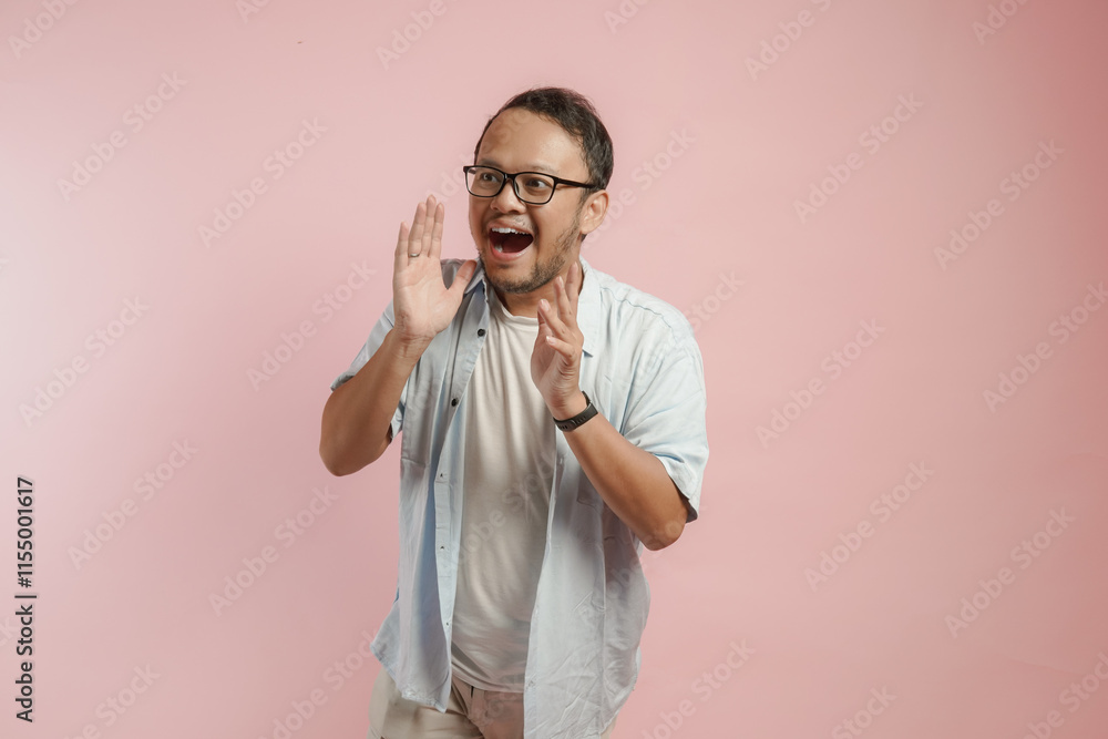 Handsome young Asian man wearing a shirt shouting and screaming loud with a hand on his mouth. Handsome young Asian man wearing a shirt shouting and screaming loud with a hand on his mouth.