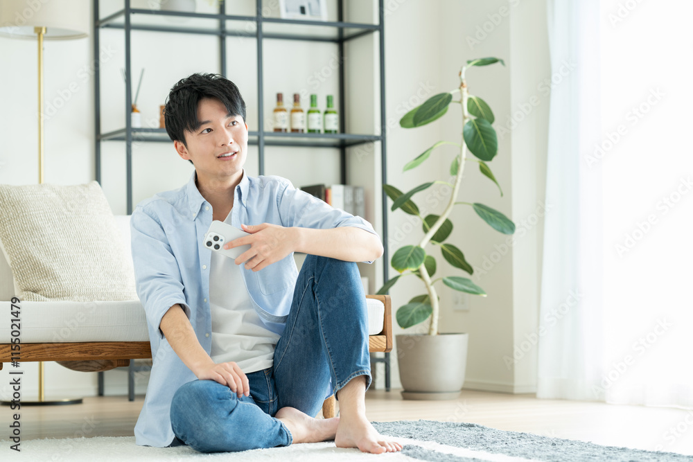 リビングでスマホを見る若い男性