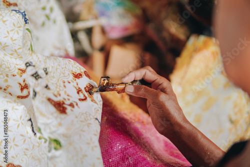 Close up picture of a person's hand drawing the design pattern of Indonesian batik tulis fabric. photo