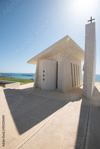 Modern minimalist christian church building overlooking tranquil ocean on sunny day photo