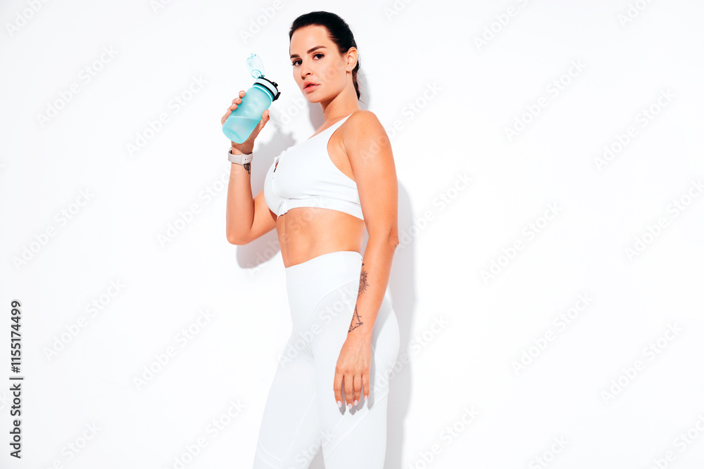 Young beautiful brunette woman in sportswear. She holds bottle of water. Portrait of serious healthy slim model. attractive sporty female drinks water after exercise workout. Isolated on white Young beautiful brunette woman in sportswear. She holds bottle of water. Portrait of serious healthy slim model. attractive sporty female drinks water after exercise workout. Isolated on white