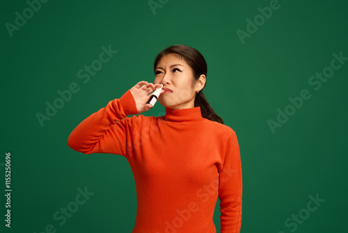 Принти на полотні Woman applying nasal spray to combat congestion, common symptom of cold or flu viruses