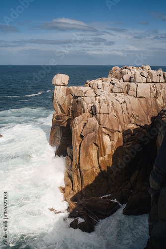 A traveler stands on the dramatic cliffs of Galicia with waves crashing below. photo