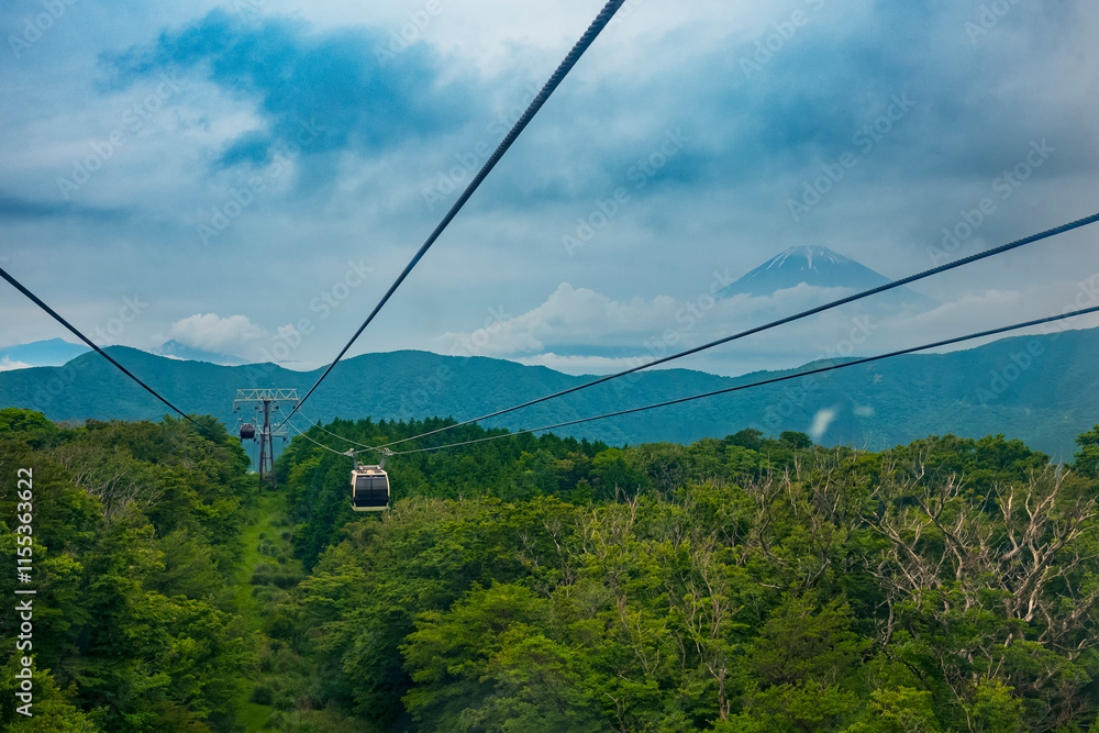 Tourists take photos of Mt. Fugi along the Mt. Komagatake Ropeway during a cloudy, summer day. The attraction is a popular Japanese travel destination. Tourists take photos of Mt. Fugi along the Mt. Komagatake Ropeway during a cloudy, summer day. The attraction is a popular Japanese travel destination.