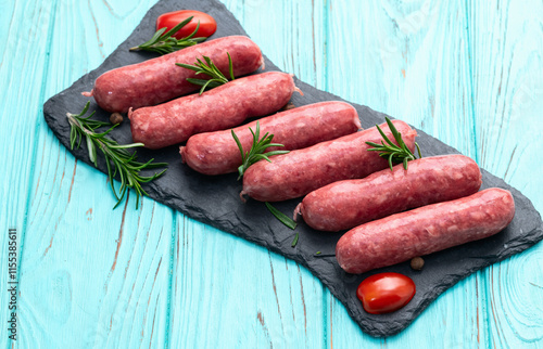 Raw beef sausages with rosemary and tomatoes photography . Top view