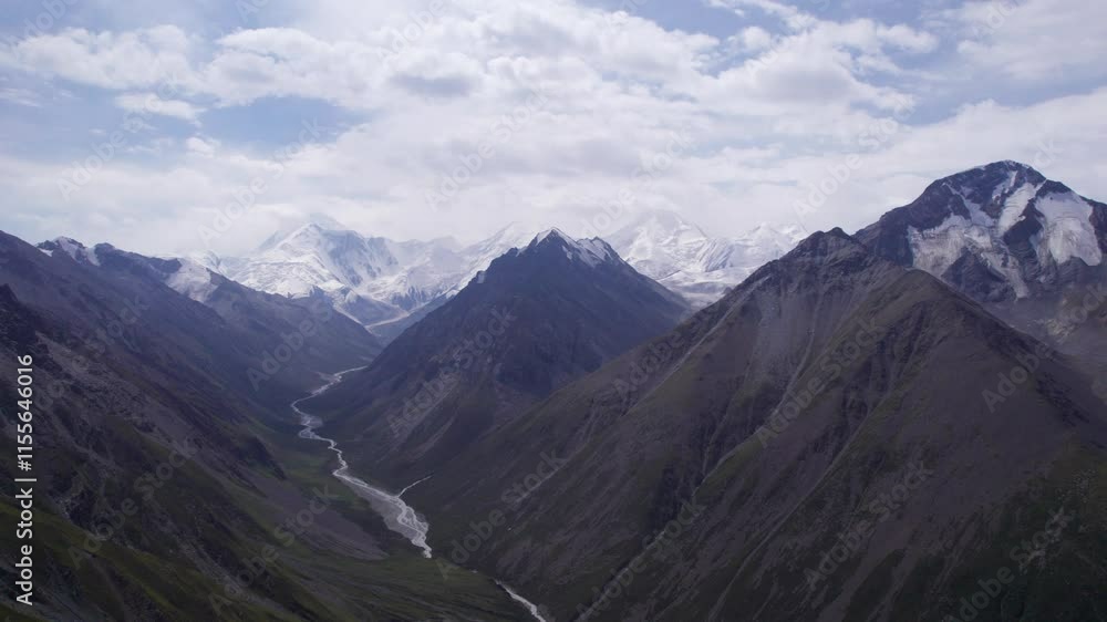 View of the gorge with snow peaks in the distance. The drone is flying smoothly. A river runs through the gorge. High mountains with the majestic peak of Khan Tengri. A marble wall made of ice. Cloudy View of the gorge with snow peaks in the distance. The drone is flying smoothly. A river runs through the gorge. High mountains with the majestic peak of Khan Tengri. A marble wall made of ice. Cloudy