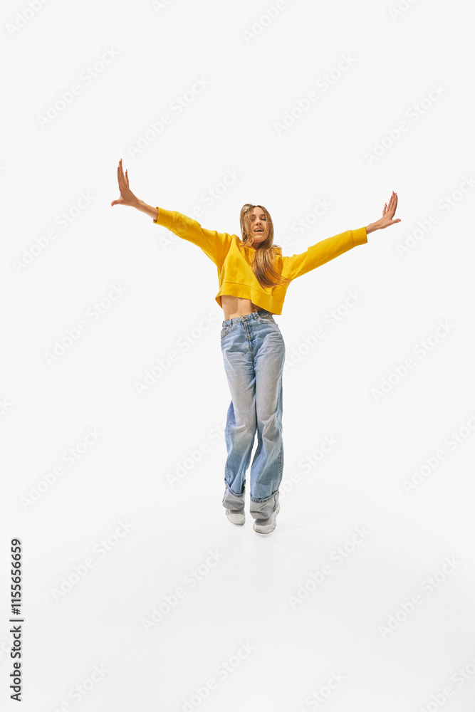 Woman in vibrant yellow sweater and casual blue jeans standing confidently with arms stretched wide and relaxed posture against white studio background. Concept of success, professional, movement. Ad Woman in vibrant yellow sweater and casual blue jeans standing confidently with arms stretched wide and relaxed posture against white studio background. Concept of success, professional, movement. Ad