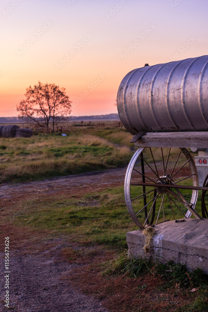 A rusty wheelbarrow sits in a field with a tree in the background A rusty wheelbarrow sits in a field with a tree in the background