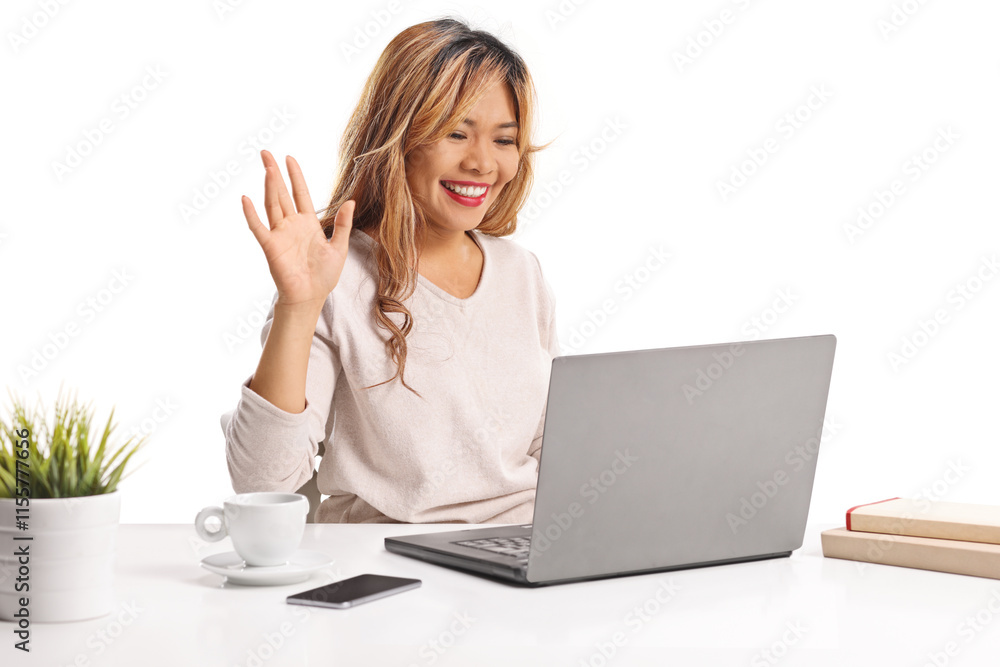 Asian woman making a video call and waving in front of a laptop Asian woman making a video call and waving in front of a laptop