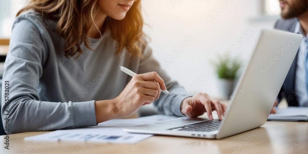 Woman Working on Laptop with Pen in Modern Office Woman Working on Laptop with Pen in Modern Office