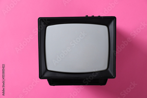 Retro tv set on pink background, top view