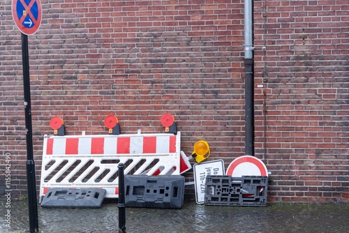 Construction site barrier and signs leaning against brick wall