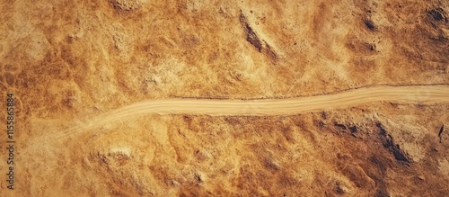 Aerial perspective of a deserted road winding through arid terrain under a clear blue sky with ample space for text or overlay. photo