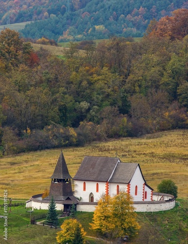 Picturesque autumn mountain landscape with hills, meadows and romantic historic wooden building at colorful sunset. The village of Cerin near Banska Bystrica, Slovakia photo