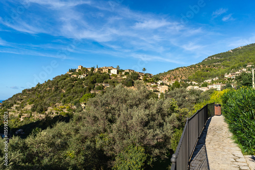 Deia, Mallorca, Spain 26.10.2021 Stone paved walking path with metal railing overlooking Mediterranean hillside village and mountain scenery