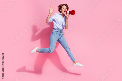 Full length photo of overjoyed pretty person jump communicate loudspeaker toa empty space ad isolated on pink color background photo