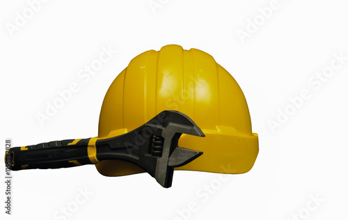 Adjustable wrench leaning on a yellow hard hat symbolizing construction work