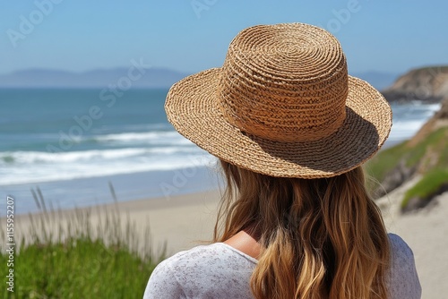 Woman wearing straw hat enjoys serene beach view with ocean waves under clear...