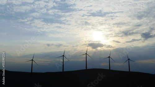 Wind power plant towers in mountains at sunset. Windmill farm. Sustainable energy production. Green energy, clean power, clean energy concept.	