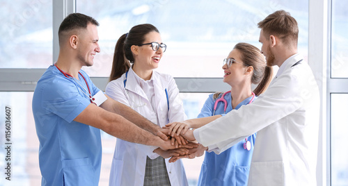 Team of doctors putting hands together in clinic